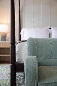 a bedroom with a bed and a green chair at Canoe Place Inn & Cottages in Hampton Bays