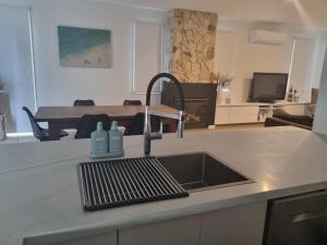 a kitchen counter with a sink and a kitchen with a table at Sand Dunes in Point Lonsdale +20 photos