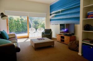 a living room with a couch and a tv and a chair at Sand Dunes in Point Lonsdale