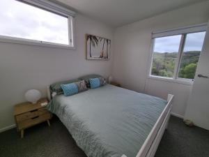 a bedroom with a bed and two windows at Sand Dunes in Point Lonsdale