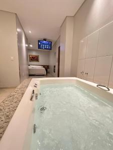 a large bathroom with a tub with a television in it at Hotel Nova Aliança in Chapadão do Sul