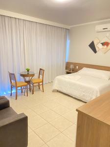 a hotel room with a bed and a table and chairs at Hotel Nova Aliança in Chapadão do Sul