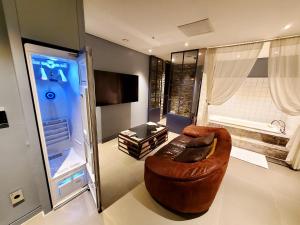 a living room with a brown couch and a television at Le Stendal Hotel in Daejeon