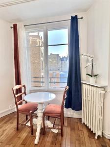 a table and chairs in a room with a window at Cosy Studio Père-lachaise-Pelleport in Paris