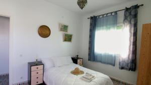 um quarto com uma cama branca e uma janela em zina surf house em Oualidia