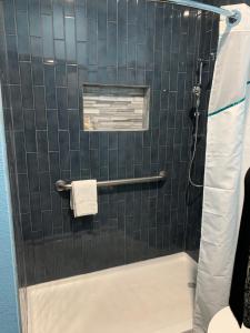 y baño con ducha y pared de azulejos. en HomeTowne Studios by Red Roof San Antonio E - Frost Bank Center, en San Antonio