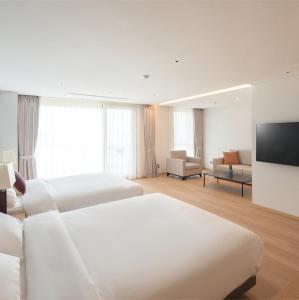 a hotel room with two beds and a flat screen tv at C-One Resort Jaeundo in Sinan