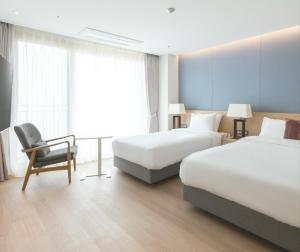 a hotel room with two beds and a chair at C-One Resort Jaeundo in Sinan +42 photos