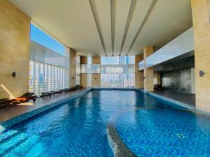 ein großer Pool in einem Gebäude mit einem großen Fenster in der Unterkunft Habitare Apart Hotel Rasuna Jakarta Powered by Archipelago in Jakarta