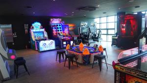 Sinan的住宿－C-One Resort Jaeundo，一间设有许多街机游戏、桌子和凳子的房间