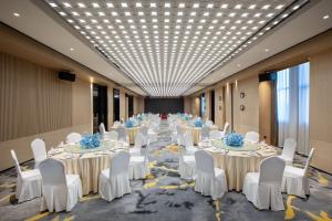 une rangée de tables avec des chaises blanches et des fleurs bleues. dans l'établissement Wingate By Wyndham Wuhan Optics Valley, à Wuhan