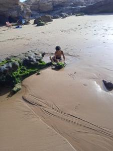 un hombre sentado en la arena en la playa en Havre de paix pied dans l'eau en Agadir