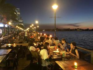 a group of people sitting at tables at a restaurant by the water at Jesselton Quay Seaview Homestay with free 1 parking by StayPlace in Kota Kinabalu