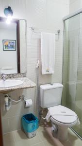 een badkamer met een toilet, een wastafel en een spiegel bij Belaris Hotel antes Hotel Costa do Calhau in São Luís