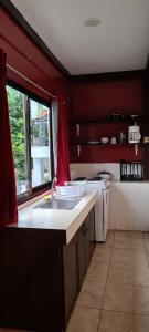 cocina con fregadero y pared roja en Paradise Comfort, en Koror