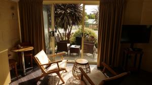 een woonkamer met stoelen en een glazen schuifdeur bij Portside Motel in Port Campbell