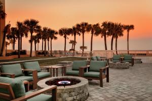 a patio with chairs and a fire pit with palm trees at Holiday Inn Hotel & Suites Daytona Beach On The Ocean, an IHG Hotel in Daytona Beach