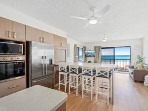 uma cozinha com um frigorífico e uma mesa com bancos de bar em Pacific Breeze - Hosted by Burleigh Letting em Gold Coast