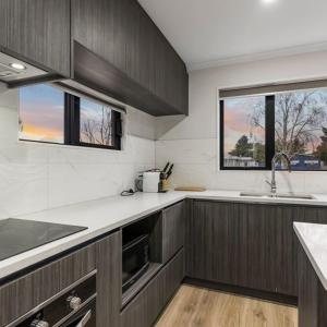 a kitchen with wooden cabinets and a sink and a window at Jupiter St Holiday Home No 3 in Auckland