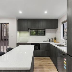 a kitchen with black cabinets and a white counter top at Jupiter St Holiday Home No 3 in Auckland