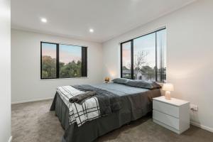 a bedroom with a large bed and two windows at Jupiter St Holiday Home No 3 in Auckland