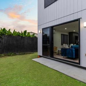 a house with a large sliding glass door with a patio at Jupiter St Holiday Home No 3 in Auckland