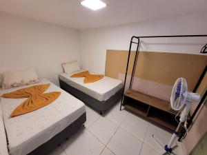 Duas camas num pequeno quarto com uma ventoinha. em Self Hostel em São Paulo