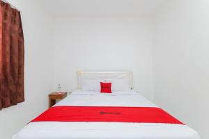 a white bed with a red pillow on it at RedDoorz near RSUD Banten Serang in Banjar