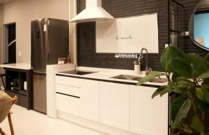 uma cozinha com armários brancos e um frigorífico de aço inoxidável em Poolvilla Remember em Pocheon