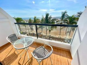 a balcony with a table and chairs and palm trees at ADDA Pacasmayo in Pacasmayo