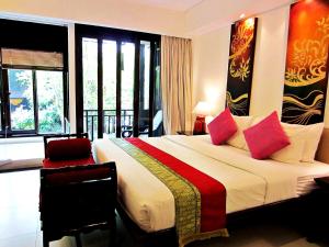 una habitación de hotel con una cama grande con almohadas rosas en Yantarasri Resort, en Chiang Mai