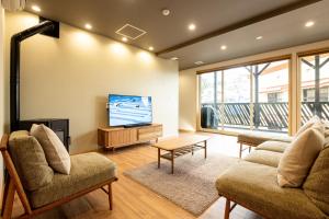 sala de estar con 2 sillas y TV de pantalla plana en Tanuki Nozawa en Nozawa Onsen