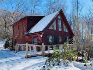 een blokhut in de sneeuw met een hek bij Spectacular Log Cabin Home 45 minutes to Asheville in Marion