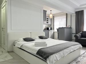 - une chambre blanche avec un grand lit et des serviettes dans l'établissement Студия в скандинавском стиле, à Pavlodar