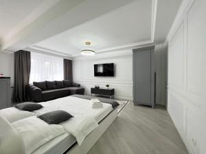 a white bedroom with a large bed and a couch at Студия в скандинавском стиле in Pavlodar