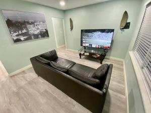 a living room with a black leather couch and a flat screen tv at Serene renovated oasis near downtown area in Gainesville
