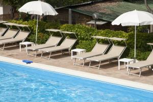 a group of chairs and umbrellas next to a pool at Il Frantoio Camping in San Bartolomeo al Mare