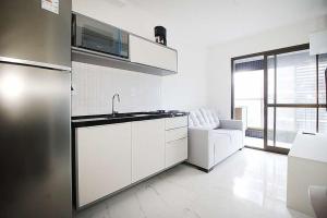 cocina blanca con fregadero y microondas en Refúgio acolhedor com vista mar e piscina compartilhada, en Salvador