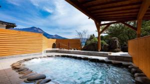 a hot tub in a backyard with a wooden fence at YUFUIN O-YADO YUKI ONSEN in Yufuin