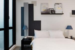 1 dormitorio con 1 cama con sábanas blancas y detalles azules en EST KL Sentral Bangsar Kuala Lumpur en Kuala Lumpur
