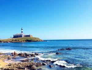 un faro sentado en la cima de una playa con el océano en Ap com Decor Charmosa e Localização Privilegiada, en Salvador