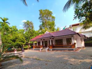 a building with a red roof on a street at Kizhakkethottam Homestays-River View Villa in Pala