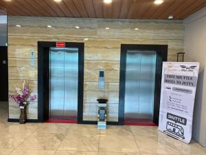 two elevators in a building with a sign on the wall at Wing Tat Grand Hotel in Semporna