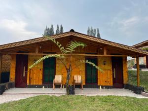 ブラスタギにあるUlina Homestay VIP Berastagiの木造家屋(椅子2脚、ヤシの木付)
