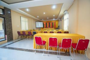 a conference room with a long table and red chairs at RedDoorz Syariah @ Jalan Gajah Mada Meulaboh in Meulaboh