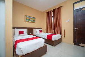 - une chambre avec 2 lits et des oreillers rouges dans l'établissement RedDoorz Syariah @ Jalan Gajah Mada Meulaboh, à Meulaboh