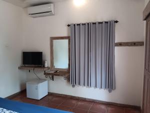 a room with a curtain and a tv and a mirror at Mango 5 Hotel in Amed