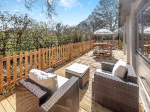 a patio with chairs and a table and an umbrella at Little Yew Tree Lodge in Hambledon