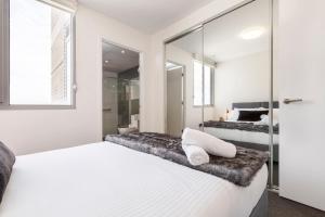 a bedroom with a white bed and a glass wall at In the heart of Richmond - 1693 in Melbourne