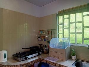a kitchen with a counter with a stove and a sink at Rania Lovely Hut Homestay Kundasang in Kundasang